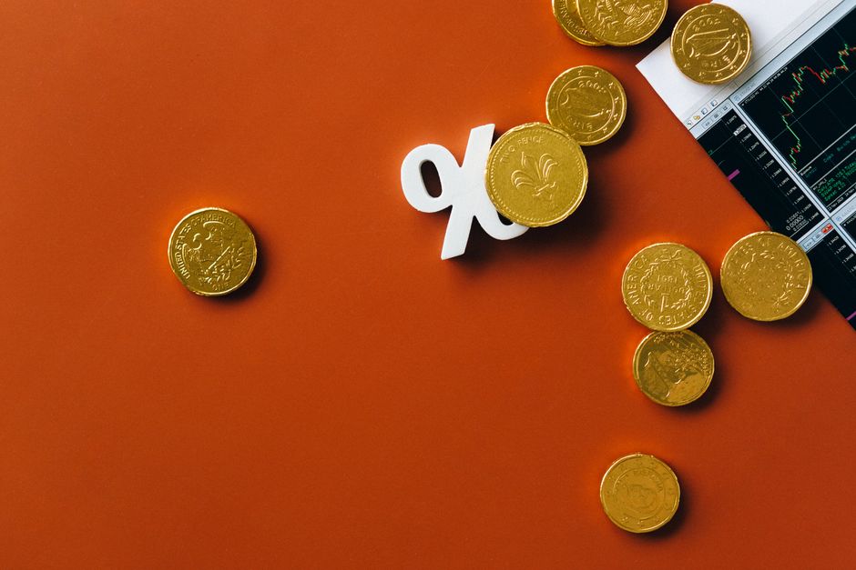 한국 금융시장 동향 — 2026년 7월 18일(토) — Gold coins scattered with a stock market graph and a percentage symbol on an orange background.