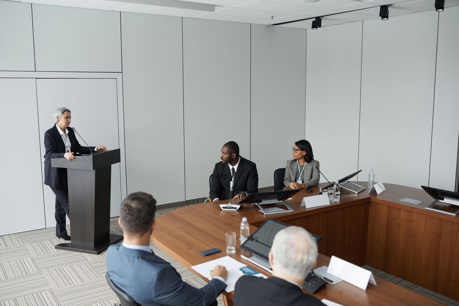 한국 금융시장 동향 — 2026년 8월 25일(화) — Diverse group of professionals in a formal meeting setting with a speaker at the podium.