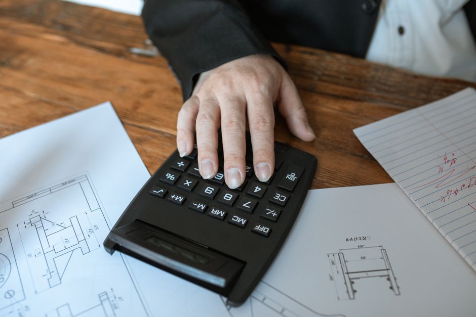 한국 금융시장 동향 — 2026년 8월 27일(목) — Hand using calculator for architectural calculations on blueprints.