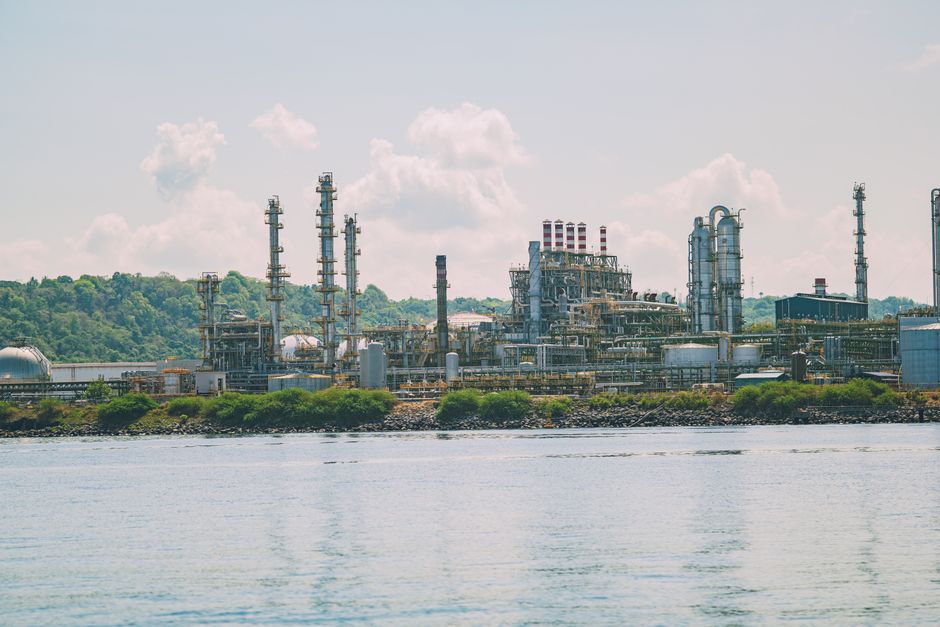 한국 금융시장 동향 — 2026년 9월 25일(금) — A large oil refinery situated by the water with bright green foliage in the background; clear blue skies and clouds overhead.