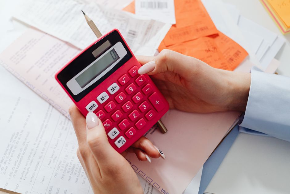 한국 금융시장 동향 — 2026년 9월 27일(일) — Close-up of hands holding a red calculator, managing finances with documents and receipts.