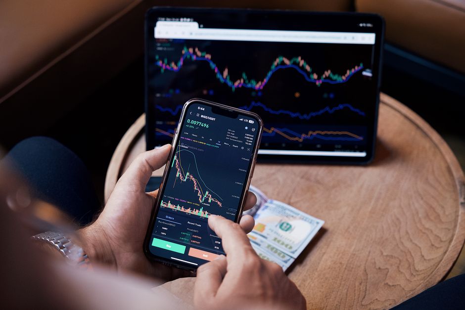 한국 금융시장 동향 — 2026년 10월 7일(수) — Close-up of a person trading stocks using a smartphone and a tablet.